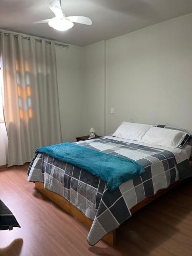 a bedroom with a bed with a blue blanket on it at Hospedagem Casa de Déo in Domingos Martins