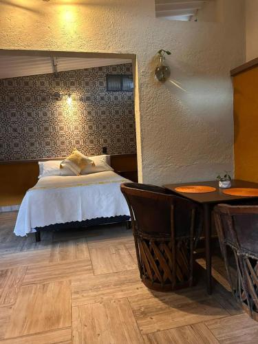 a bedroom with a bed and a table and a table and chairs at El Bungalow de Juana in Tepoztlán