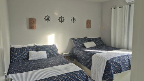 a room with two beds with blue and white sheets at Flat Mar doce lar in Conde