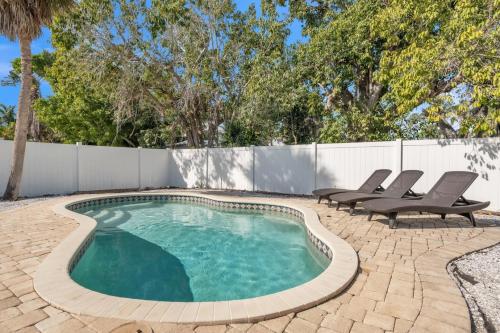 a swimming pool with chairs and a fence at Island Gem B home in Anna Maria