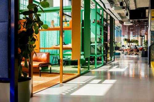 a hallway with chairs and tables and a plant at The Social Hub Delft Extended Stay in Delft