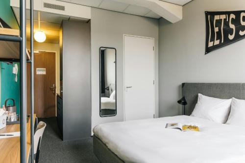 a hotel room with a bed and a mirror at The Social Hub Rotterdam Extended Stay in Rotterdam