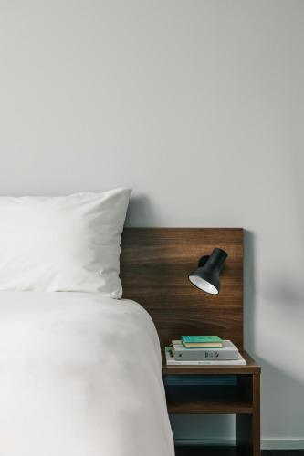 a bed with a table with a lamp and a book at The Social Hub Rotterdam Extended Stay in Rotterdam