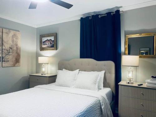 a bedroom with a white bed with blue curtains at The Hourglass Inn- Unit B in Savannah