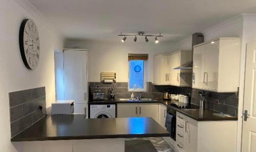a kitchen with white cabinets and a black counter top at Modern 2 Bedroom Ground Floor Apartment with Parking Ripon City Centre in Ripon