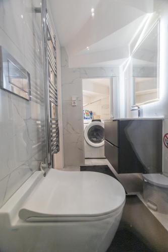 a bathroom with a toilet and a washing machine at varkiza luxury 2BD apartment in Varkiza