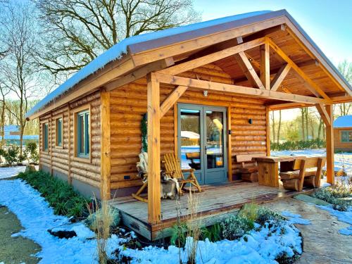 a log cabin with a porch and a table at Magnolia Hoeve - Unieke Bestemming voor Paardenliefhebbers en Bijzondere Overnachtingen in de natuur in Ledeacker
