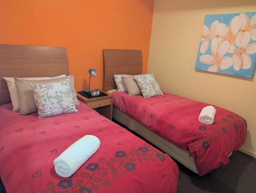a bedroom with two beds with red sheets and a pillow at Landmark Resort 518 - Casablanca Penthouse 5th Floor in Nelson Bay