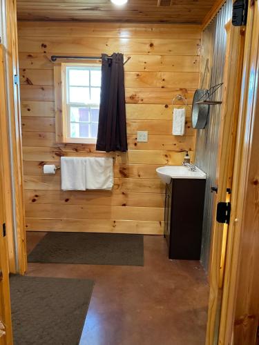 a wooden bathroom with a sink and a window at Blue Cozy Cottage in Oneida
