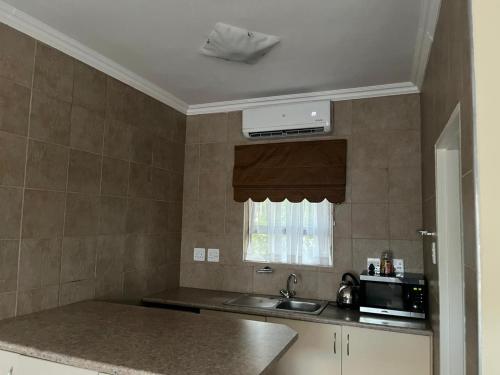 a kitchen with a sink and a microwave at Matthys Guesthouse in Kimberley