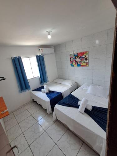 two beds in a room with blue curtains at Apartamento Ryso do Mar Porto de Galinhas in Porto De Galinhas