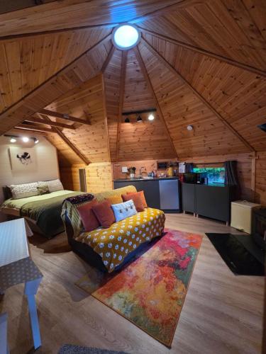 a bedroom with a couch and a bed in a room at The Hive - Unique log cabin with wood burning stove in Ludchurch