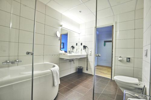 ein Badezimmer mit Badewanne, Toilette und Waschbecken in der Unterkunft Hotel Frøya in Sistranda
