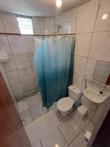 a bathroom with a toilet and a blue shower curtain at Apartamento Ryso do Mar Porto de Galinhas in Porto De Galinhas