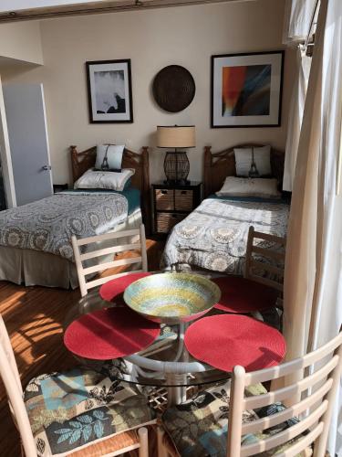 a room with two beds and a table and chairs at Stunning 2BD 2BA Ocean Front Condo Great View, AC in Wailuku