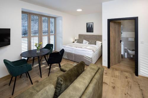 a bedroom with a bed and a couch and a table at Vila Eduarda Grohmanna in Vrbno pod Pradědem
