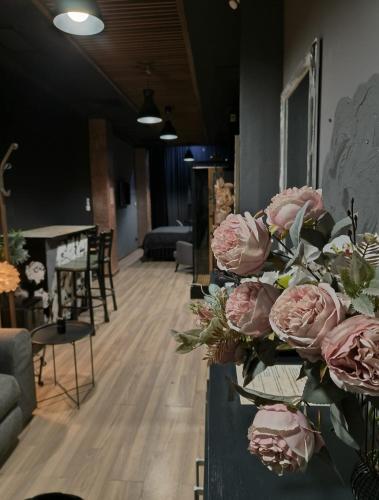 a bouquet of pink roses on a table in a room at KALI Old Town LOFT with Monument view in Bucharest