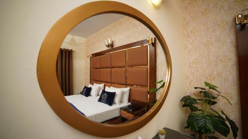 ein Schlafzimmer mit einem Bett und einem großen Spiegel in der Unterkunft Orchid Inn by WIH in Karatschi