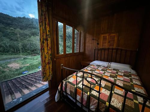 a bedroom with a bed and a window with a view at Refugio da Serra - Cachoeira dos Bufalos in Pindamonhangaba