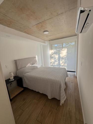 a white bedroom with a bed and a window at Apartamento Piriapolis in Piriápolis