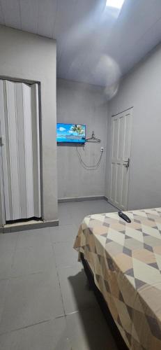 a bedroom with a bed and a tv on the wall at Quarto com otima localização in Manaus