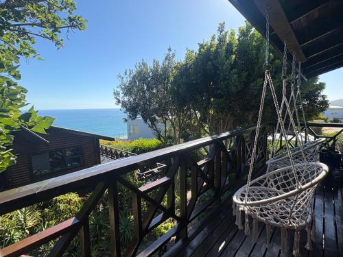 a porch with a swinging chair on a deck at Sunny studio in the sky in Brenton-on-Sea