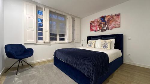 a bedroom with a bed and a blue chair at FERREIRA'S HOUSE Guimarães in Guimarães