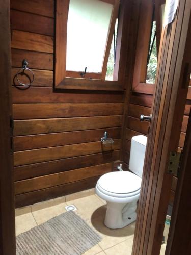 a bathroom with a toilet in a room with wooden walls at Refúgio eco Lodge in Nova Friburgo