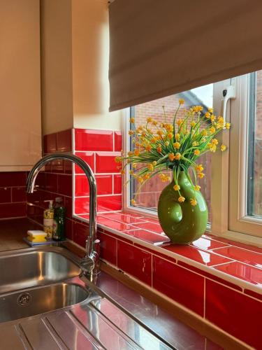 a kitchen sink with a vase of flowers in a window at Mill House in West Bromwich