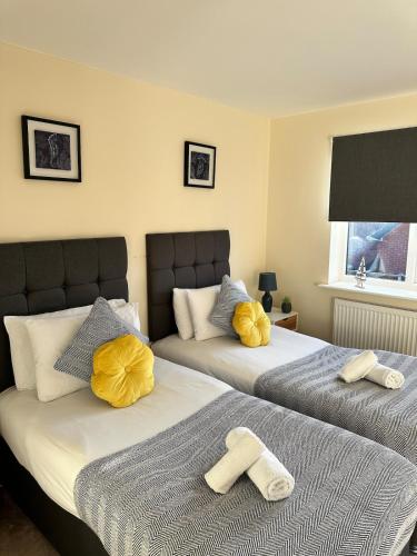 two beds in a bedroom with yellow towels on them at Mill House in West Bromwich