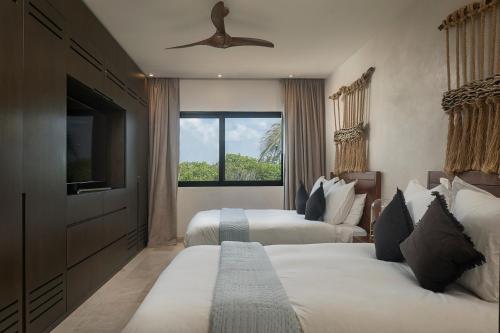 a hotel room with two beds and a television at Luxury 3BR Apartmen Tankah Beach plus Rooftop in Tulum