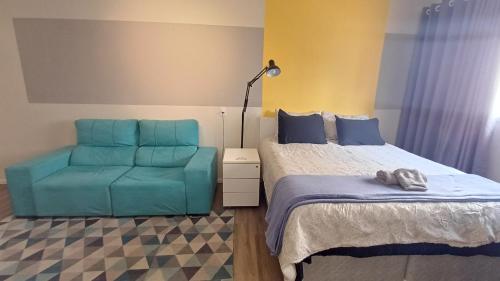 a bedroom with a bed and a blue chair at Barreto Leme Studio 12 in Campinas