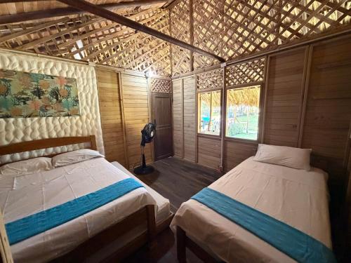 a bedroom with two beds in a wooden house at Cabaña con Deck Frente al Mar para 8 personas in Moñitos