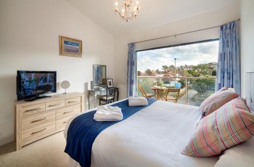 a bedroom with a bed and a large window at BEACHES - South Sands beach house in Torquay