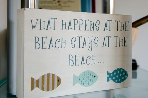 a sign that reads what happens at the beach stays at the beach at BEACHES - South Sands beach house in Torquay