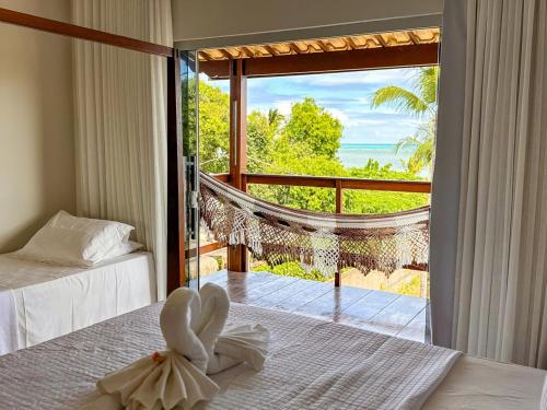 a bedroom with a view of the ocean from a balcony at Villa Manoá in São Miguel dos Milagres