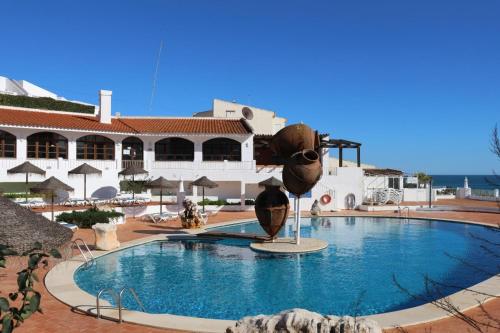 a large pool with a statue in front of a building at Casa Salema Praia Clube in Salema