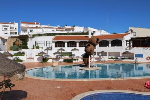a large swimming pool with a statue in front of a building at Casa Salema Praia Clube in Salema