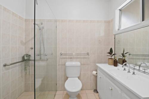 a bathroom with a shower and a toilet and a sink at Mildas Cottage Hunter Valley in Cessnock