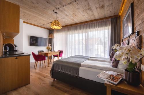 a bedroom with a bed and a table and a kitchen at APARTAMENTY U HARREGO BOUTIQUE SPA masaże, sauna, tężnia solankowa , balkon , taras , klimatyzacja , parking in Kudowa-Zdrój