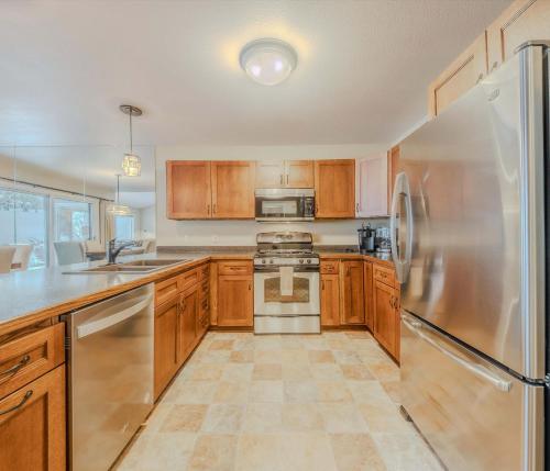a kitchen with wooden cabinets and a stainless steel refrigerator at Meadow Lake Townhouse For 6ppl in Columbia Falls