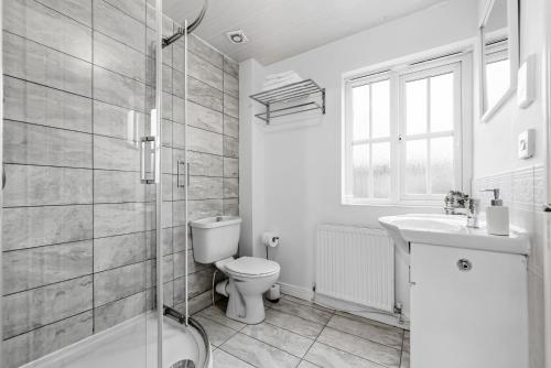 a bathroom with a toilet and a sink and a shower at Comfort Lodge - Modern 5 bed house w 2 bathrooms, parking & gardens in Solihull