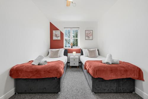 two beds in a room with red walls at Comfort Lodge - Modern 5 bed house w 2 bathrooms, parking & gardens in Solihull