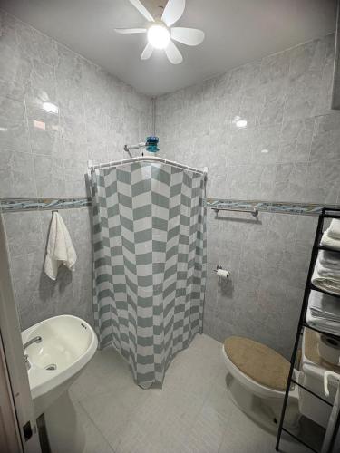 a bathroom with a shower curtain and a toilet and a sink at Departamento céntrico y cómodo La Casona in Xalapa