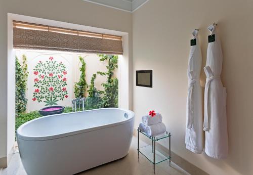 a white bath tub in a bathroom with a window at The Oberoi Sukhvilas Spa Resort, New Chandigarh in Chandīgarh