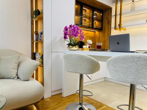 a kitchen with a counter with a laptop and two chairs at SOL LUX Tuzla in Tuzla