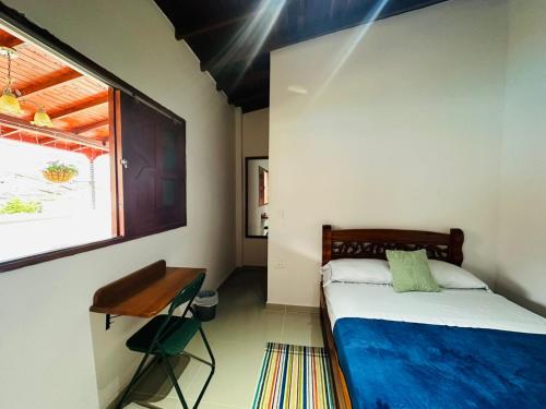 a bedroom with a bed and a desk and a window at Hotel Jardin de Rosas in Jardin