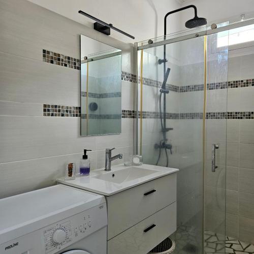 a white bathroom with a sink and a shower at Charmante villa bord de mer les pieds dans l'eau in La Trinité