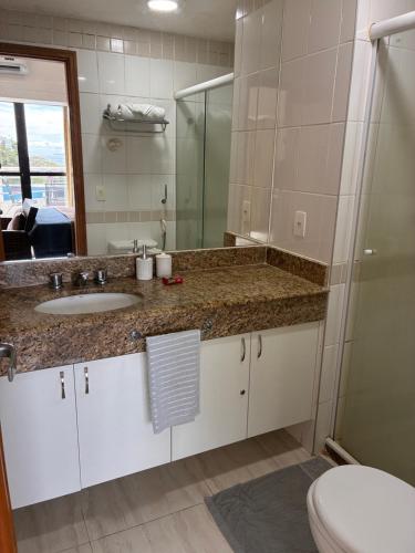 a bathroom with a sink and a toilet and a mirror at Hotel tropical Manaus suite luxo in Manaus