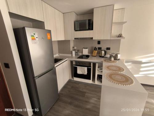 a kitchen with white cabinets and a refrigerator at Departamento Piso 6 in Puerto Montt
